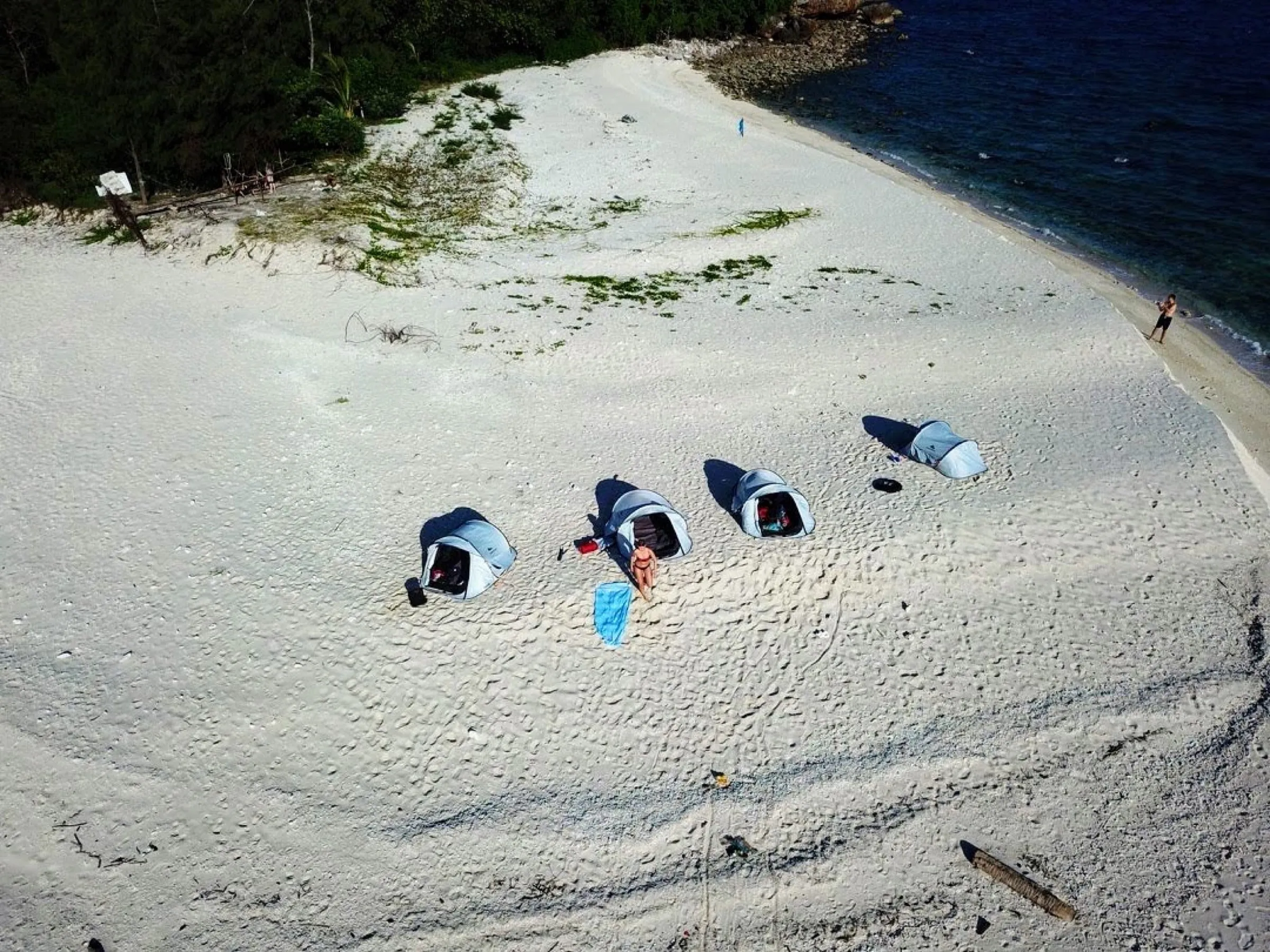 Aerial view of camping tents lined up on the white coral sand of Koh Kye.